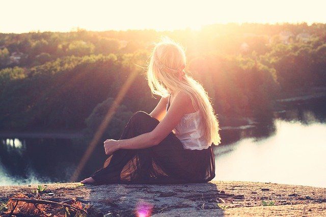 Jeune femme assise regardant un lac et une forêt