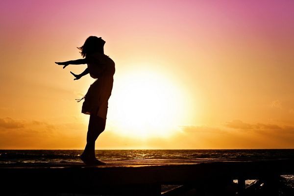Femme debout de profil au couché du soleil